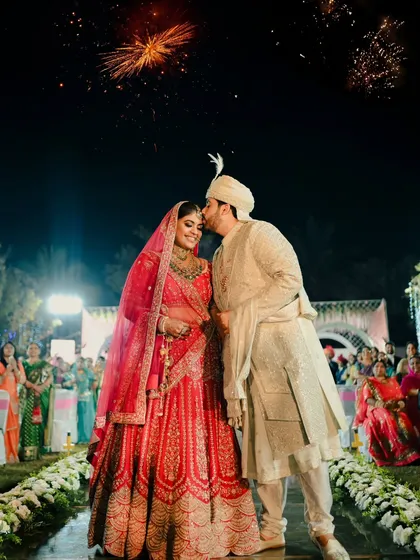 A perfect end to the ceremony. The groom kisses his bride on the forehead as fireworks go off in the background.