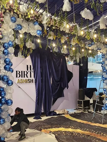 My team working on the stage area for a massive birthday party, combining a floral and balloon arch with a custom backdrop.