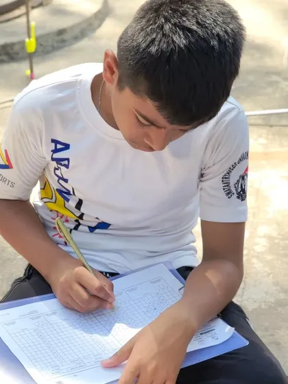 A young archer meticulously filling out a score sheet. We teach responsibility and attention to detail.