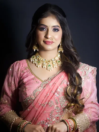 A soft and elegant look in a pink saree. The makeup features a beautiful purple smokey eye and a neutral lip, perfect for a wedding guest or bridesmaid.