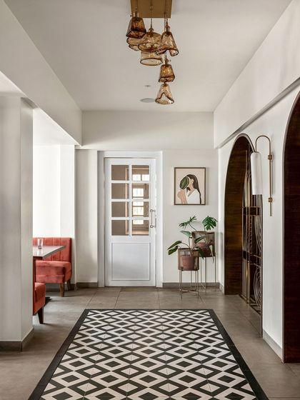 The hallway connects different dining zones with intentional design. I used a classic black-and-white tile pattern to honor the heritage feel, while a custom-made bell-jar chandelier adds a unique, modern touch.