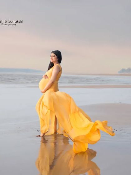 A vibrant splash of sunshine on the shore. The bright yellow gown flows beautifully in the sea breeze, creating a joyful and eye-catching maternity photo against the reflective wet sand.