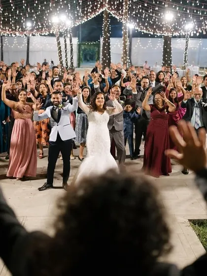 The entire wedding party joins in for a group dance. This wide shot captures the collective joy and energy of the celebration, with the couple at the center of it all.