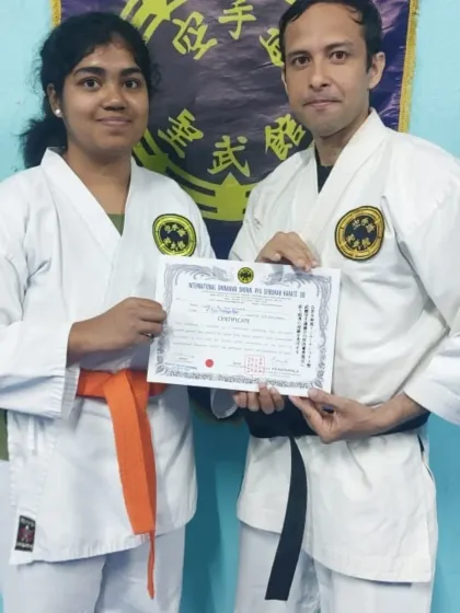 Presenting a student with her certificate for achieving the rank of 7th Kyu (orange belt). Her hard work in mastering the fundamentals of Shorin-Ryu is evident.