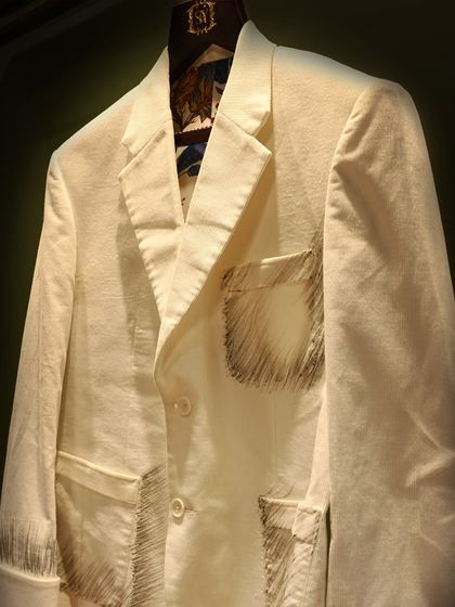 Another angle of the white blazer with sketch embroidery. This view highlights the texture of the fabric and the unconventional yet artistic detailing.