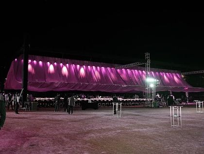 The full view of the long dinner table under a dramatic pink-lit canopy.