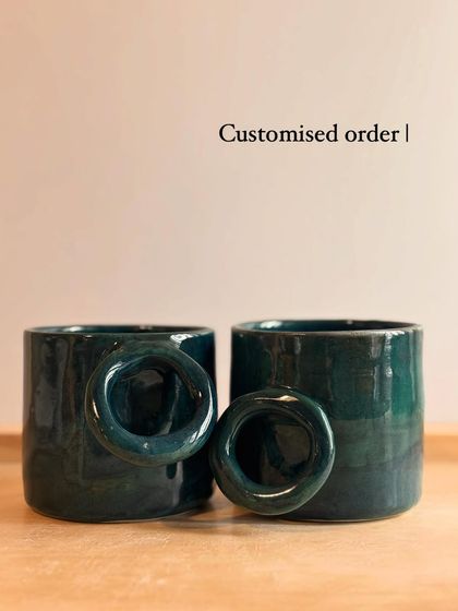 A pair of custom-ordered mugs with a unique circular handle, finished in a deep Forest Green glaze.
