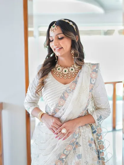 A full-length shot of the bride in her beautiful white lehenga, the jewellery adding a touch of regal elegance.