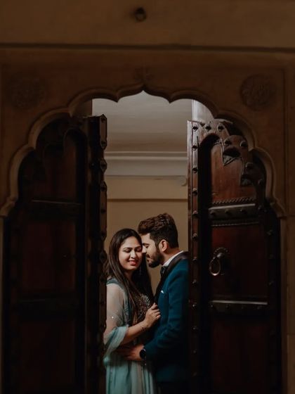 A quiet, romantic portrait of the couple framed in a dark wooden doorway, creating a sense of intimacy and privacy.