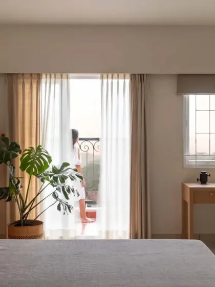 A wide view of the master bedroom, showing the calm color palette, minimalist furniture, and the connection to the outdoor balcony.