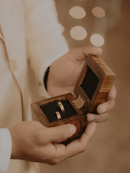 A close-up of the groom holding the wooden ring box, just moments before the proposal.