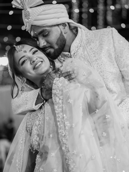 A joyful black and white portrait of the groom lifting his bride. This classic shot is full of happiness and romance.