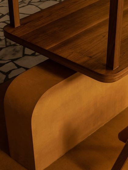 We believe in the beauty of simple forms and honest materials. This detail from the Grid Pavilion shows the gentle curve of a Jaisalmer stone base meeting a polished teak wood surface, a quiet moment of material harmony.