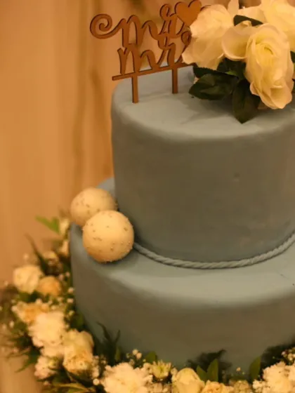 A two-tiered wedding cake with a "Mr & Mrs" topper and fresh floral decorations. We design bespoke cakes that serve as a beautiful centerpiece for your special day.
