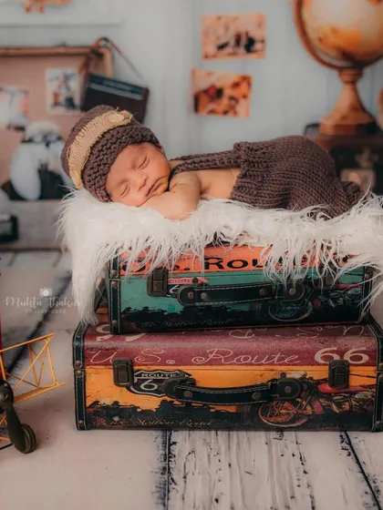 This shot shows a full creative setup for a newborn session. With a 'little traveler' theme, I used vintage suitcases, maps, and a tiny knitted outfit to create a unique and dreamy portrait for this 11-day-old baby boy.