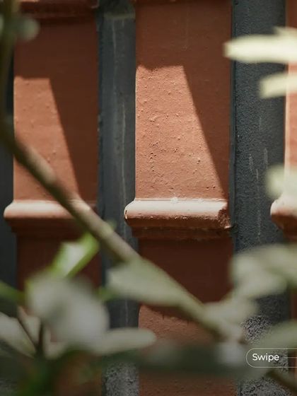 A close-up of the terracotta pillars at the Manjunath Residence, with sunlight creating beautiful shadows that highlight their texture.
