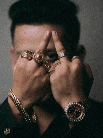 A bold and unconventional detail shot. The focus on the hands and rings, obscuring the face, creates a moody and intriguing portrait that highlights the groom's unique style and accessories.