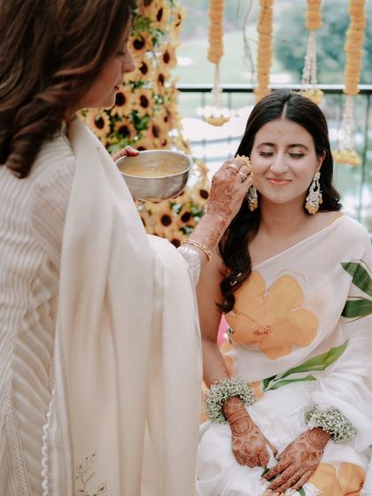 A serene moment during the Haldi ceremony. The gentle application of turmeric and the bride's calm expression make for a beautiful, candid shot.