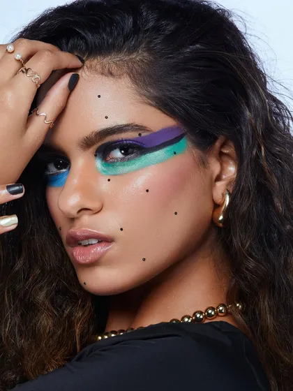 A creative graphic eye look with blocks of color and scattered dots, showing a playful and modern approach to makeup.