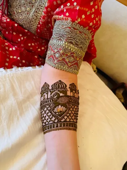 I love creating unique accent pieces like this custom armband. It features a regal peacock amidst architectural elements, offering a stylish and unexpected way to wear henna art for a sangeet or party.