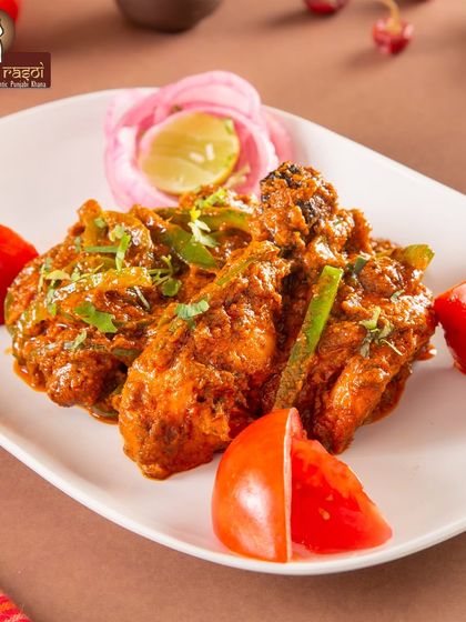 Spreading Punjabi flavor one bite at a time. This vibrant image shows our Kadai Chicken, garnished with fresh tomatoes and capsicum.