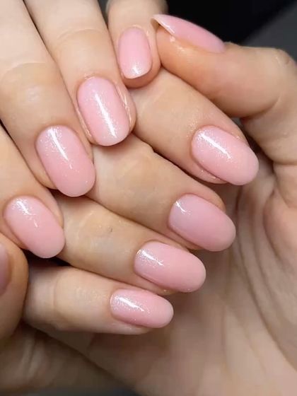 A soft, shimmery pink manicure on oval nails. The delicate sparkle adds a touch of glamour to this feminine and classic color.