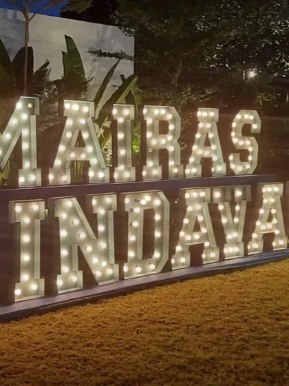 Large, illuminated marquee letters spelling out 'Mairas Vrindavan' for a Krishna-themed event. This creates a grand and impressive entrance, perfect for outdoor evening celebrations.
