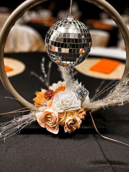 A modern and unique table centerpiece for a cocktail night. The design features a small disco ball surrounded by dried flowers and pampas grass.