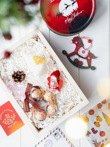 An overhead view of the Christmas hamper being assembled, showing the careful placement of each festive item.