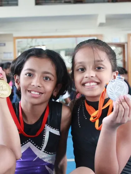 The smiles say it all. We believe every effort deserves to be celebrated, and seeing our young gymnasts proudly show off their medals from a district-level competition is our greatest reward.