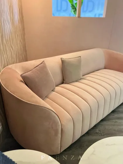 This blush pink sofa features vertical channel tufting and a curved silhouette. It's a soft, feminine piece that adds a touch of glamour and sophistication to any room.