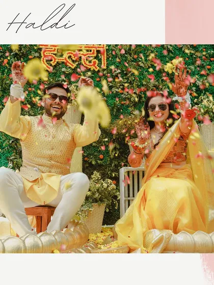 A joyous moment of celebration as the couple is showered with flower petals during their Haldi ceremony. The image is full of color, movement, and happy faces.