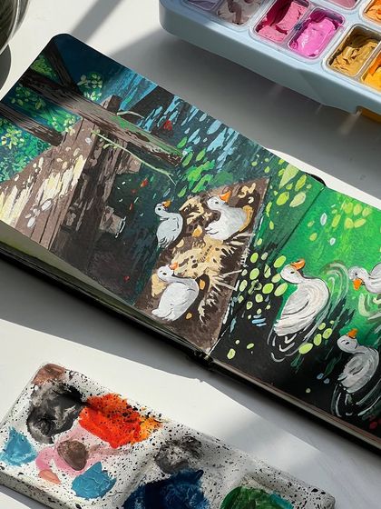 A close up of the finished duck painting in my sketchbook, next to my paint-splattered palette.