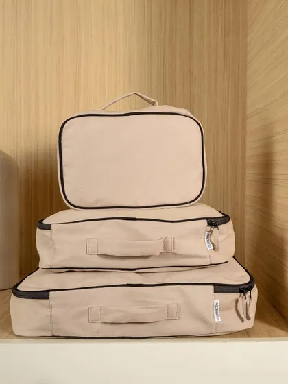 A set of Faborange's beige packing cubes, neatly stacked on a wooden shelf. This minimalist shot highlights the product's organizational function and clean aesthetic.