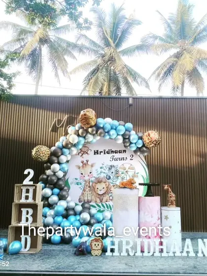 An outdoor jungle theme with a beautiful backdrop of palm trees. The blue, grey, and animal print balloons create a cool and modern safari look.