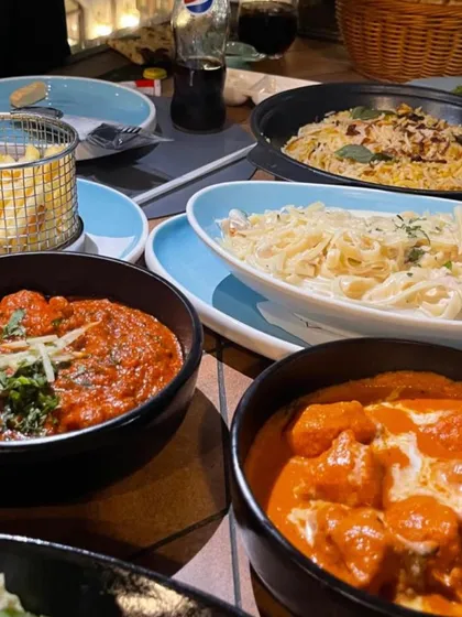 For those who love variety, I create family-style feasts with a mix of cuisines. This table features bowls of classic Indian curries like butter chicken alongside creamy pasta dishes, catering to every taste.