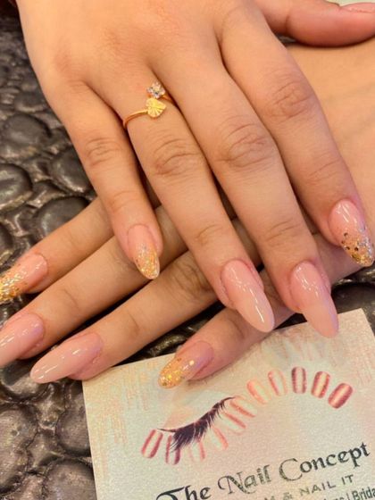 Long, elegant almond nails with a sheer nude base. The ring fingers feature a beautiful gold glitter ombre effect starting from the tips.