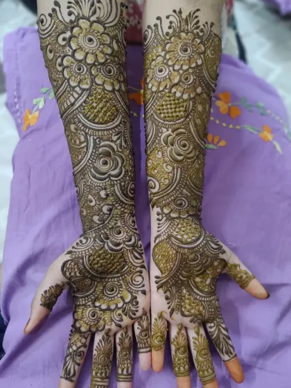 This design features bold, circular floral motifs connected by delicate vines and leaves, covering the hands and arms completely.