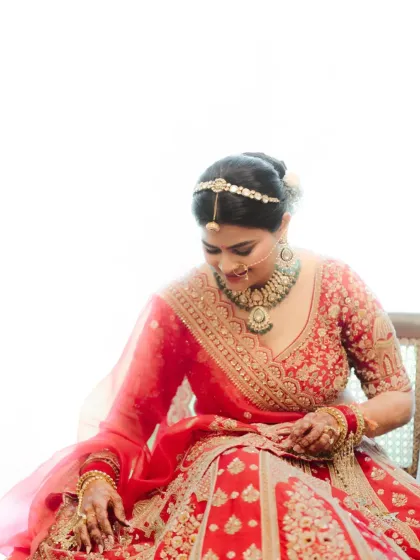 A sweet, candid bridal portrait. The bride is seated, looking down with a gentle smile, radiating a calm and happy energy.