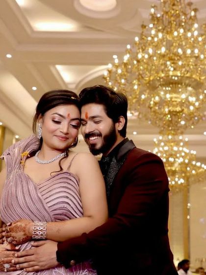 A romantic shot of the engaged couple. Her makeup features a soft, shimmery eye and a subtle lip, complementing her lilac gown, while his grooming is natural and sharp.