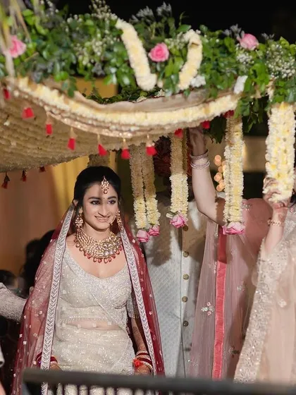 The bride's joyful face is the focus of this entry shot. Her happiness is palpable as she is escorted by her family to the wedding mandap.
