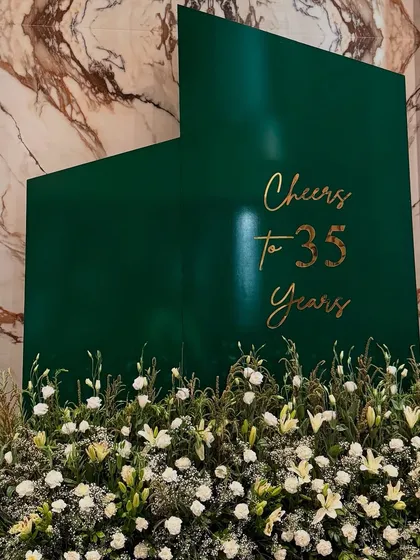 Modern, minimal, and striking. This 35th birthday celebration featured a bold emerald green backdrop with elegant gold calligraphy, set against a bed of fresh white lilies and baby's breath for a look that is both serene and sophisticated.