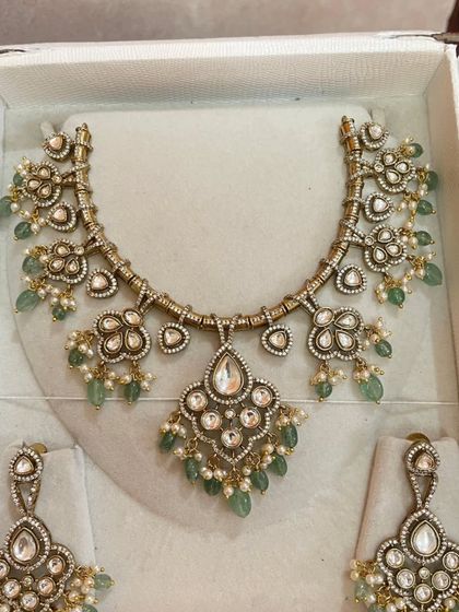 A lovely antique-finish necklace set with mint-green beads and pearl accents. The floral and heart-shaped motifs add a touch of romance.