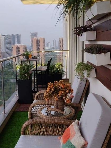 This apartment balcony was designed for relaxation with comfortable wicker chairs and a view of the city. We used a mix of artificial grass and planters to create a garden feel, complemented by a wooden accent wall with box planters.