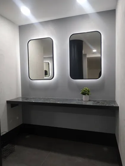 This view shows the clean, minimalist design of the grooming area. The simple material palette of gray walls and dark stone provides a calm and uncluttered environment for members post-workout.