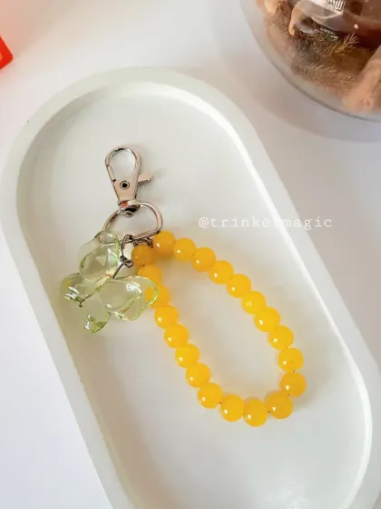 A sunny yellow beaded bag charm with a yellow butterfly, perfect for adding a bright and cheerful touch to your accessories.