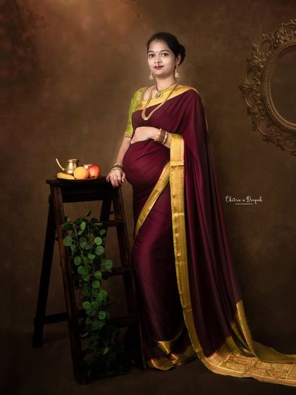 An elegant portrait featuring a mom-to-be in a beautiful saree, posed with rustic and traditional props.