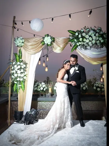 A full-length portrait of the bride and groom at their outdoor reception. The elegant floral decor and soft lighting create a magical atmosphere for their first photos as a married couple.