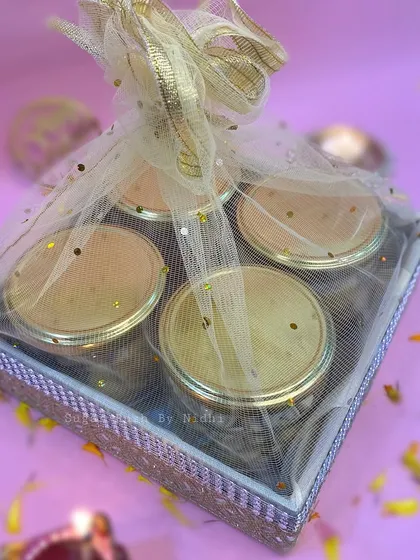 A beautifully wrapped tray hamper for Diwali, containing four jars of assorted nuts and cookies.