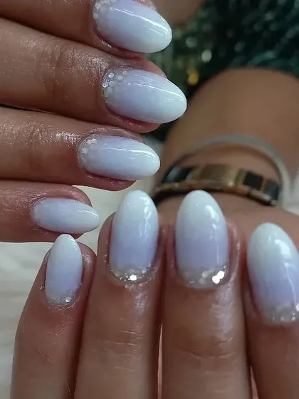A delicate and ethereal look featuring a soft white-to-lavender ombre base. A sprinkle of fine silver glitter near the cuticles gives this manicure a frosty, magical appearance.